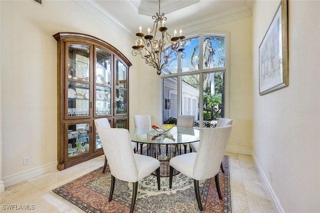 dining area with crown molding, a tray ceiling, a notable chandelier, and baseboards