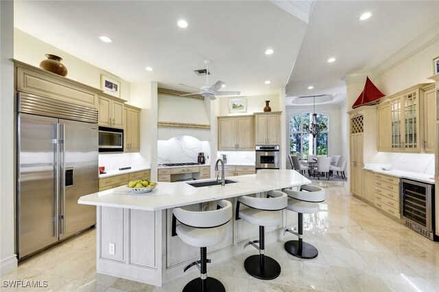 kitchen featuring visible vents, wine cooler, built in appliances, light countertops, and a sink