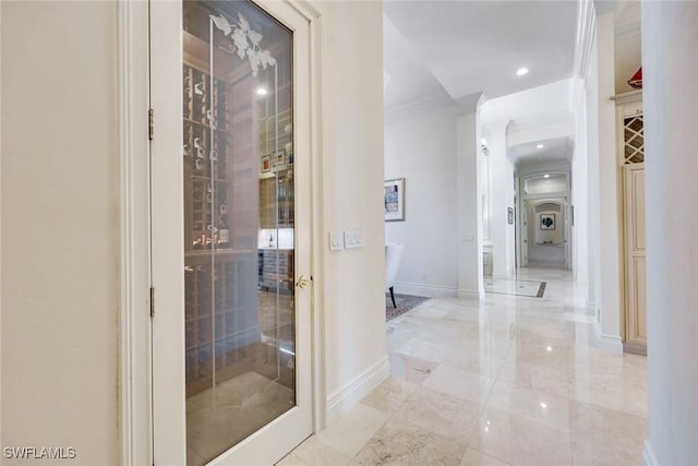 hallway featuring marble finish floor, crown molding, and baseboards