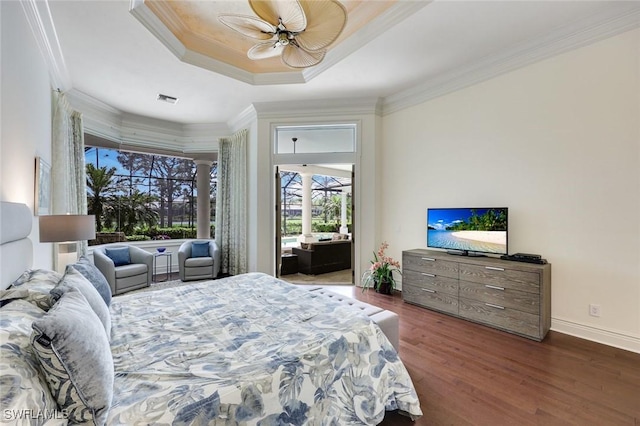 bedroom featuring wood finished floors, visible vents, baseboards, ornamental molding, and a raised ceiling