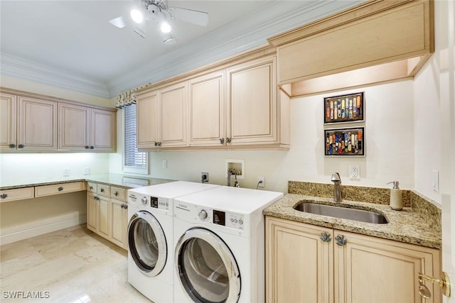 clothes washing area featuring ceiling fan, washing machine and dryer, a sink, cabinet space, and crown molding