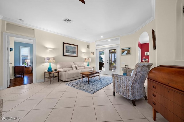 living room with arched walkways, french doors, light tile patterned floors, visible vents, and ornamental molding