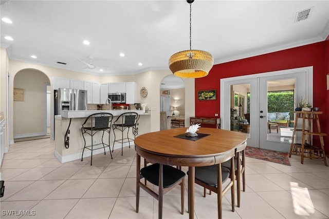 dining area featuring arched walkways, french doors, light tile patterned floors, and visible vents