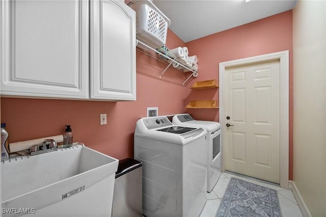 washroom with light tile patterned floors, a sink, baseboards, cabinet space, and washing machine and clothes dryer