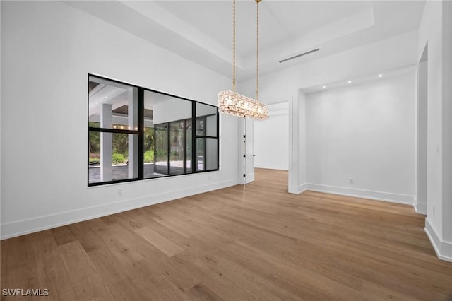 3233 64th St SW, Naples, FL 34105 - unfurnished dining area featuring wood finished floors, a chandelier, and a raised ceiling