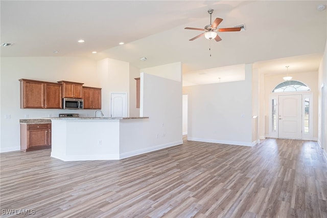 kitchen featuring open floor plan, stainless steel microwave, and brown cabinets