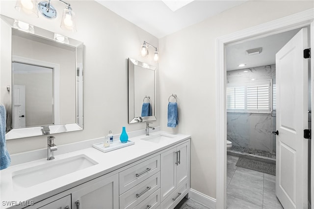 full bath featuring double vanity, toilet, a marble finish shower, and a sink