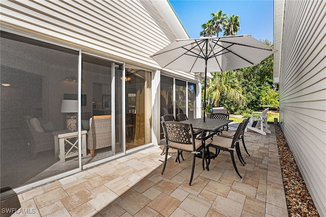 view of patio with outdoor dining area and a sunroom