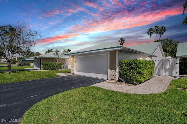 view of front of home featuring a garage, driveway, metal roof, and a front lawn