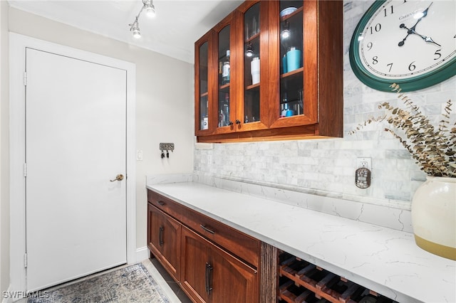 interior space featuring tasteful backsplash, glass insert cabinets, and light stone countertops