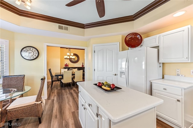 kitchen featuring white refrigerator with ice dispenser, visible vents, dark wood-type flooring, crown molding, and white cabinetry