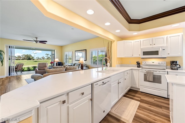 kitchen featuring white appliances, a peninsula, light countertops, white cabinetry, and a sink