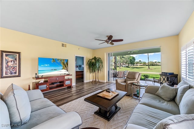 living area with ceiling fan, wood finished floors, visible vents, and baseboards