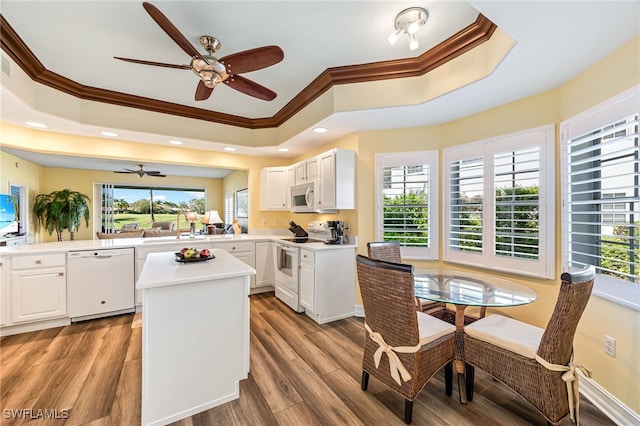 kitchen featuring white appliances, a kitchen island, a raised ceiling, and light wood-style flooring