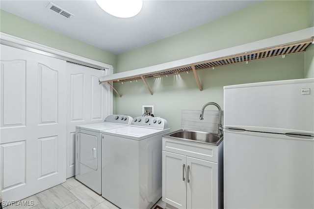 washroom featuring washer and clothes dryer, cabinet space, a sink, and visible vents