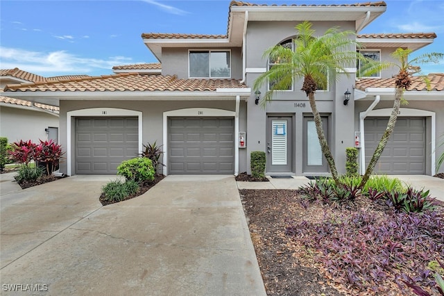 view of front facade with concrete driveway, a tiled roof, a garage, and stucco siding