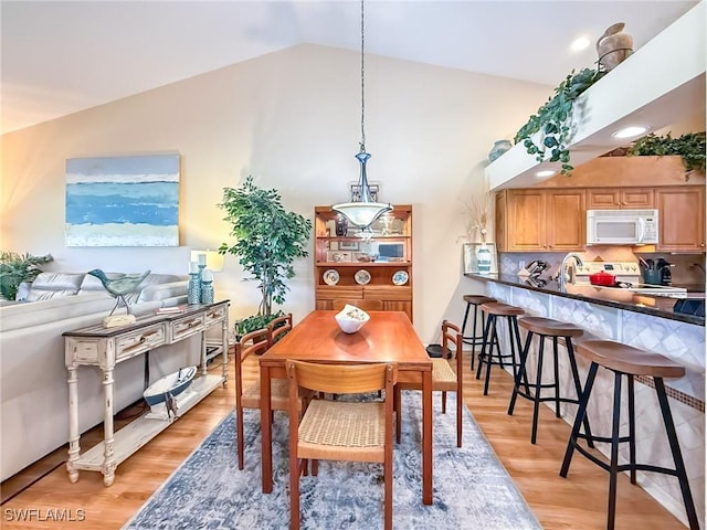 dining area with light wood finished floors and vaulted ceiling