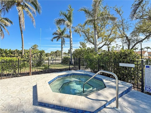 view of swimming pool featuring fence and a hot tub