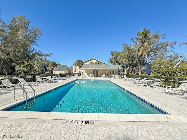 community pool with a patio area and fence