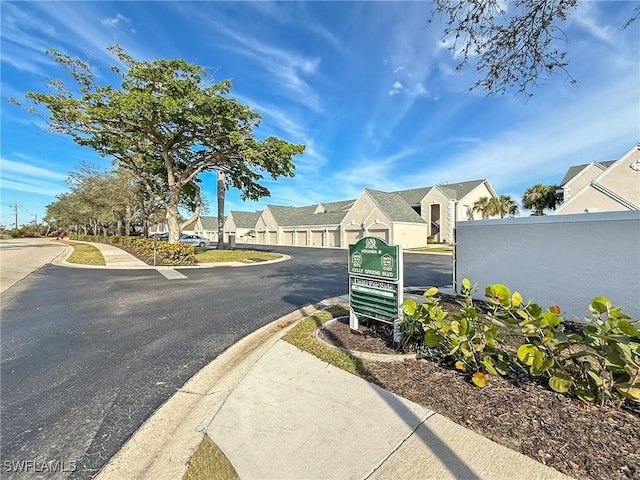 view of street with curbs, sidewalks, a residential view, and community garages