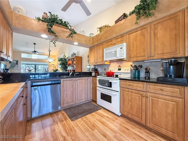 kitchen with light wood finished floors, lofted ceiling, backsplash, a sink, and white appliances