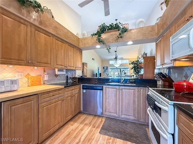 kitchen featuring light wood finished floors, ceiling fan, white appliances, and a sink