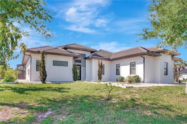 view of front of home with a front yard, a tile roof, and stucco siding