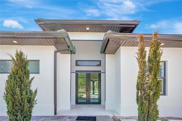 property entrance with stucco siding and french doors