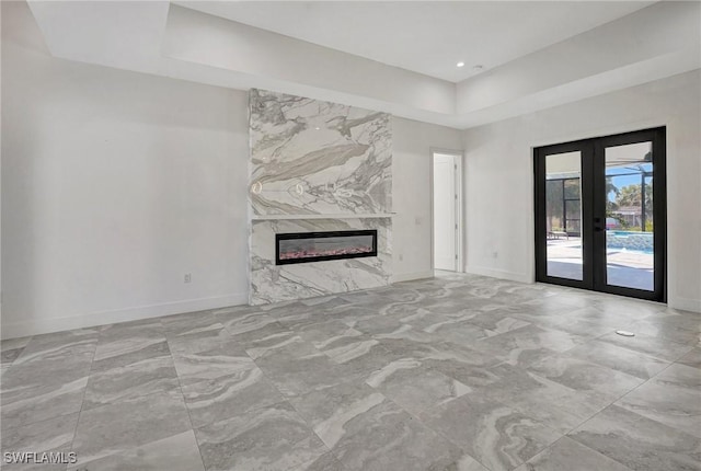 unfurnished living room featuring french doors, baseboards, and a premium fireplace