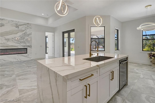 kitchen with marble finish floor, a sink, a high end fireplace, light stone countertops, and hanging light fixtures