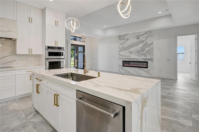 kitchen with a high end fireplace, stainless steel appliances, a tray ceiling, and a sink