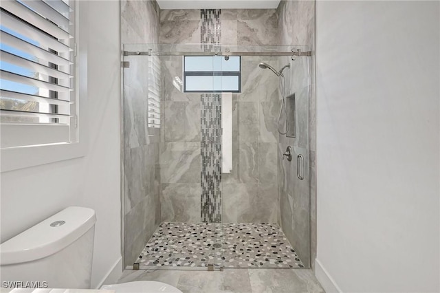 bathroom featuring baseboards, toilet, and a stall shower