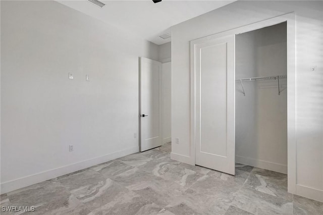 unfurnished bedroom with a closet, baseboards, and marble finish floor