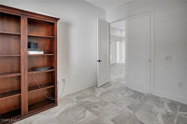 unfurnished bedroom featuring baseboards and marble finish floor