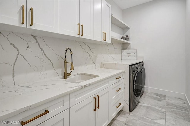 clothes washing area with baseboards, cabinet space, a sink, marble finish floor, and washer and clothes dryer