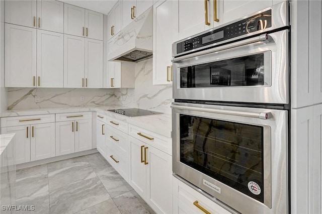 kitchen with marble finish floor, light stone counters, under cabinet range hood, stainless steel double oven, and black electric stovetop