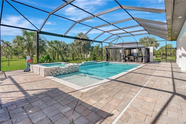 view of pool featuring glass enclosure, a pool with connected hot tub, and a patio area