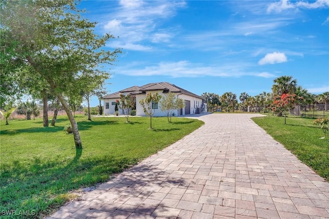 view of community with a lawn, an attached garage, and decorative driveway