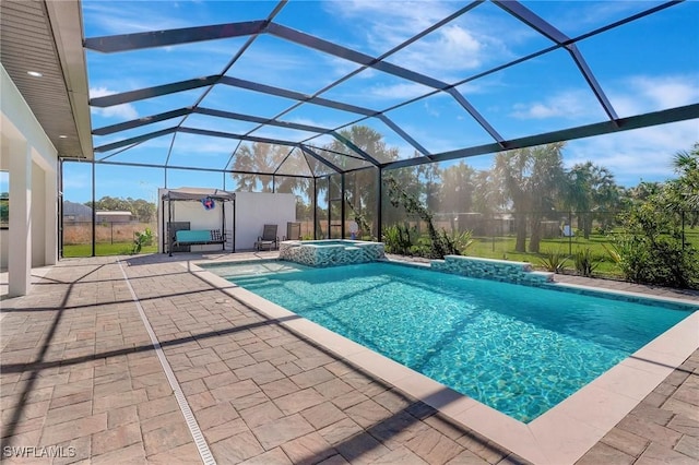 view of pool with a patio area, glass enclosure, and a pool with connected hot tub