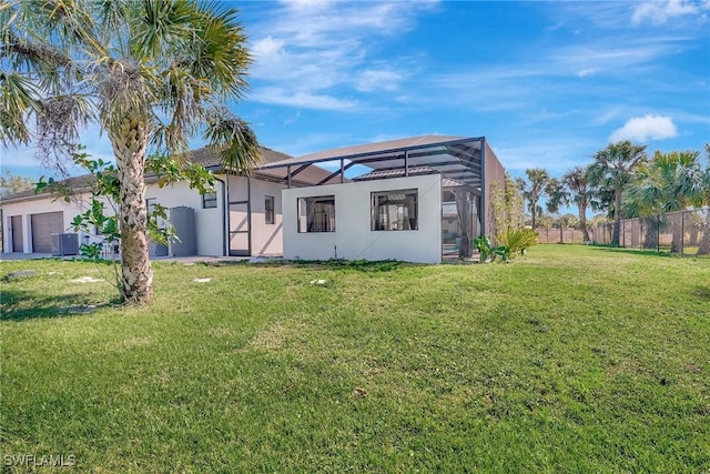 back of house featuring fence, an attached garage, a yard, central AC, and a lanai