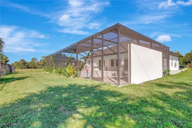 rear view of house featuring a patio, a yard, and a lanai