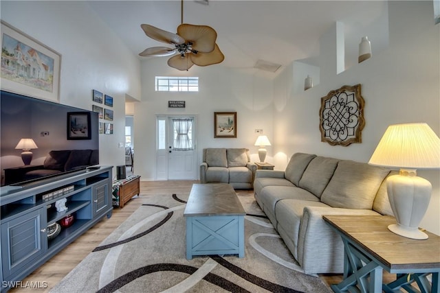 living room featuring light wood-type flooring, high vaulted ceiling, and a ceiling fan