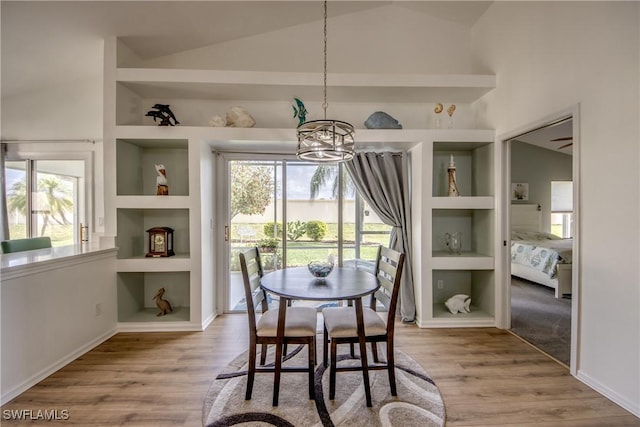 dining area with an inviting chandelier, built in shelves, and wood finished floors