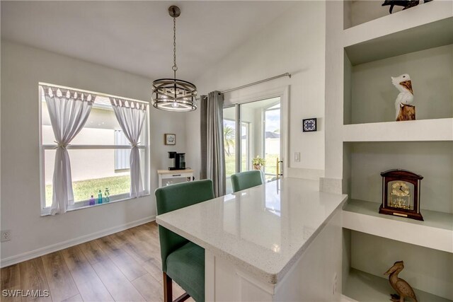 dining space with light wood finished floors, a notable chandelier, baseboards, and a wealth of natural light