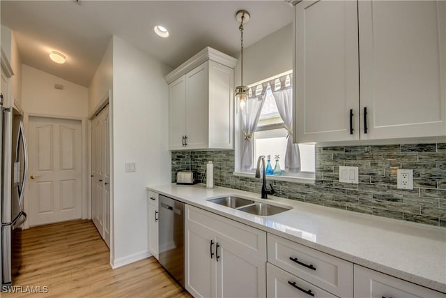 kitchen featuring light wood finished floors, tasteful backsplash, white cabinets, appliances with stainless steel finishes, and a sink