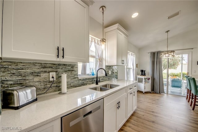 kitchen featuring visible vents, backsplash, decorative light fixtures, stainless steel dishwasher, and a sink