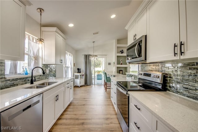 kitchen featuring visible vents, light wood-style flooring, stainless steel appliances, white cabinetry, and a sink