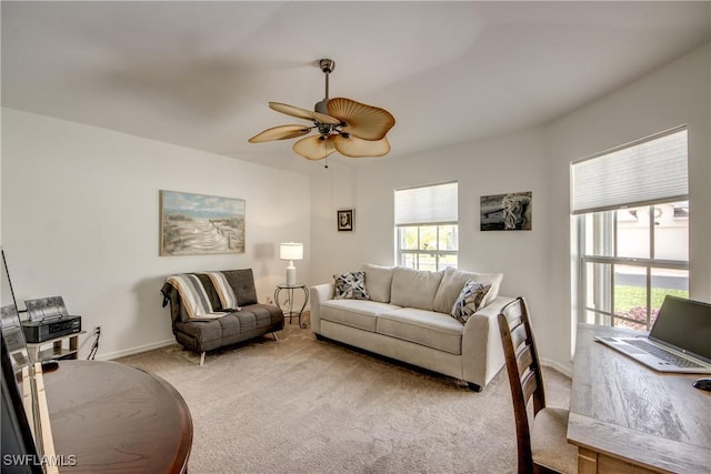 carpeted living area with baseboards and a ceiling fan