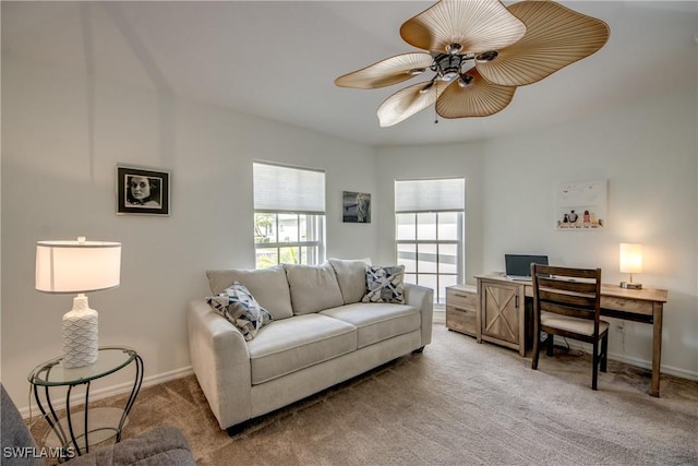 living room with baseboards, a ceiling fan, and light colored carpet