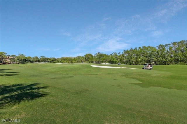 view of community featuring view of golf course and a yard